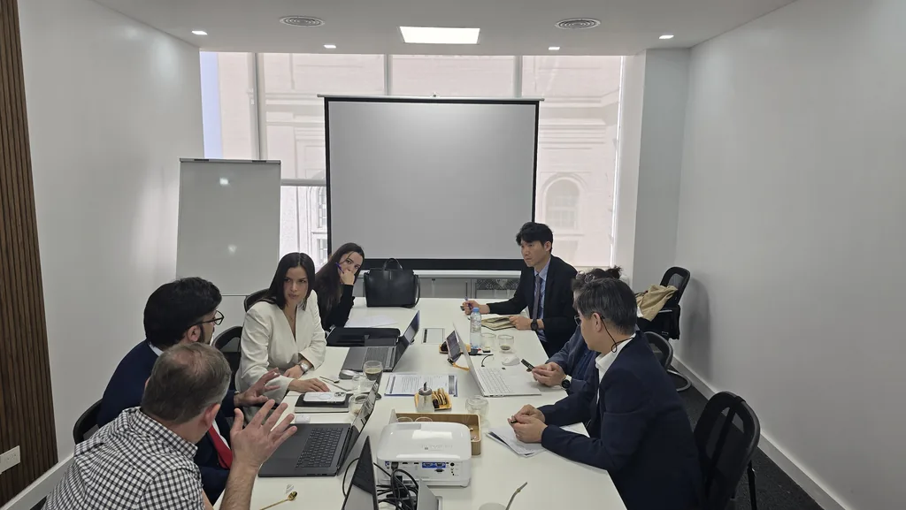Participantes reunidos alrededor de una mesa con computadoras y un proyector durante una visita institucional de G-CERTI.